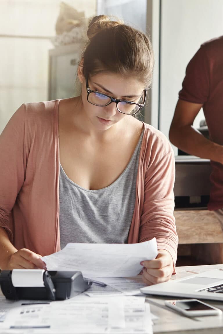 budgeting money 6 easy tips - woman at desk looking over bills