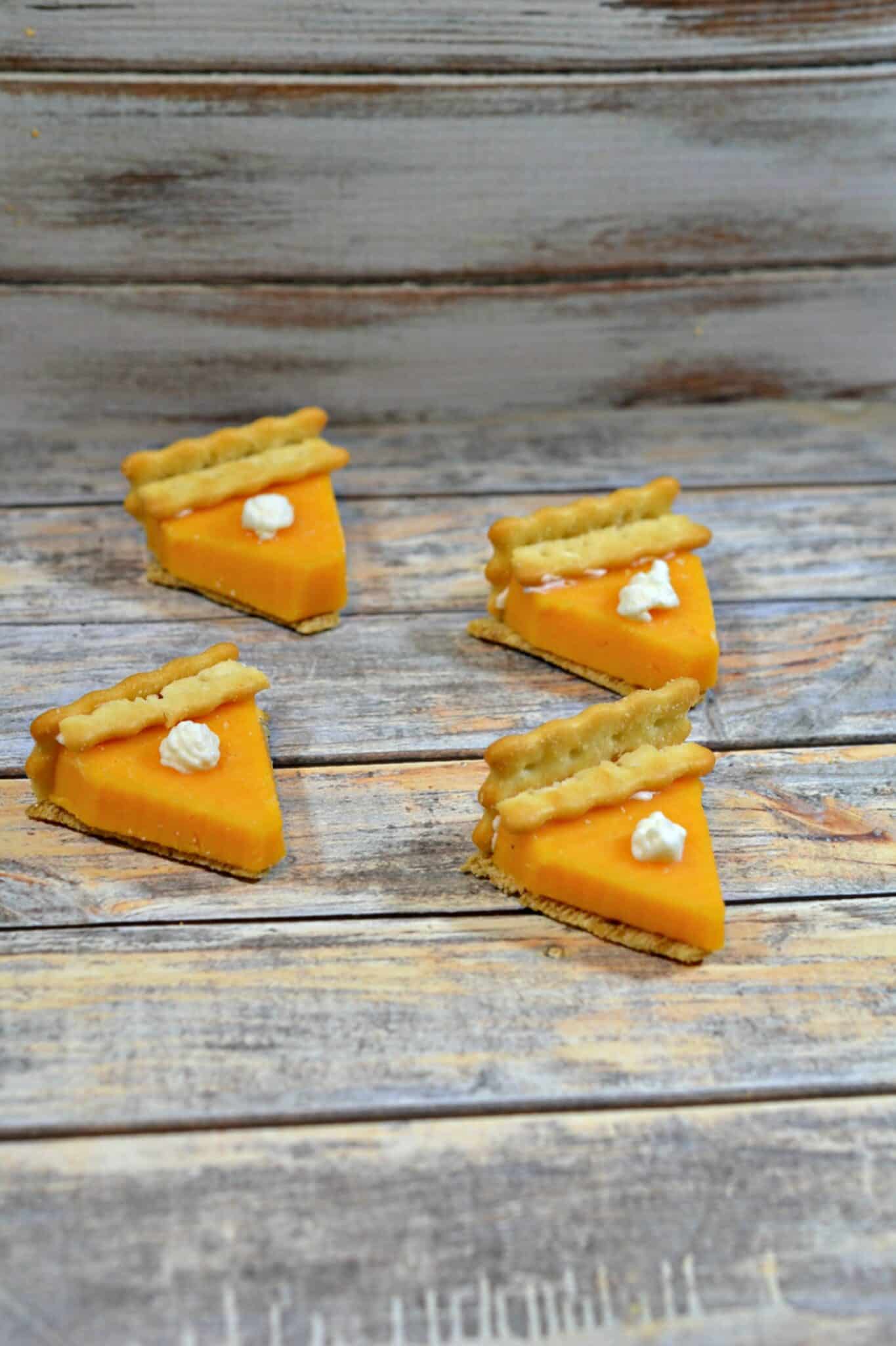 four mini pies made from crackers & cheese. Made to look like mini pumpkin pies on gray background