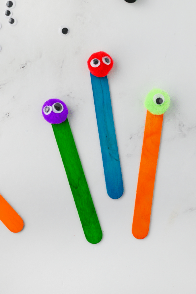 Adding eyes to monster heads on colored popsicle sticks